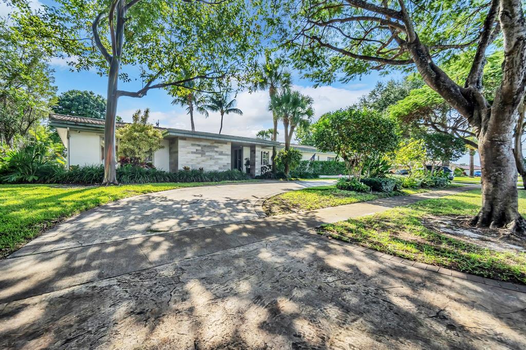 a view of a house with a yard and large trees