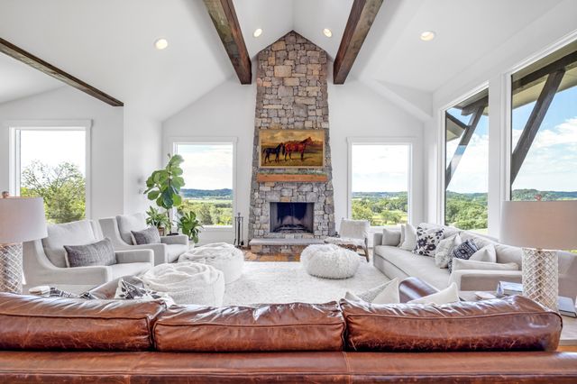 a living room with furniture fireplace and large windows