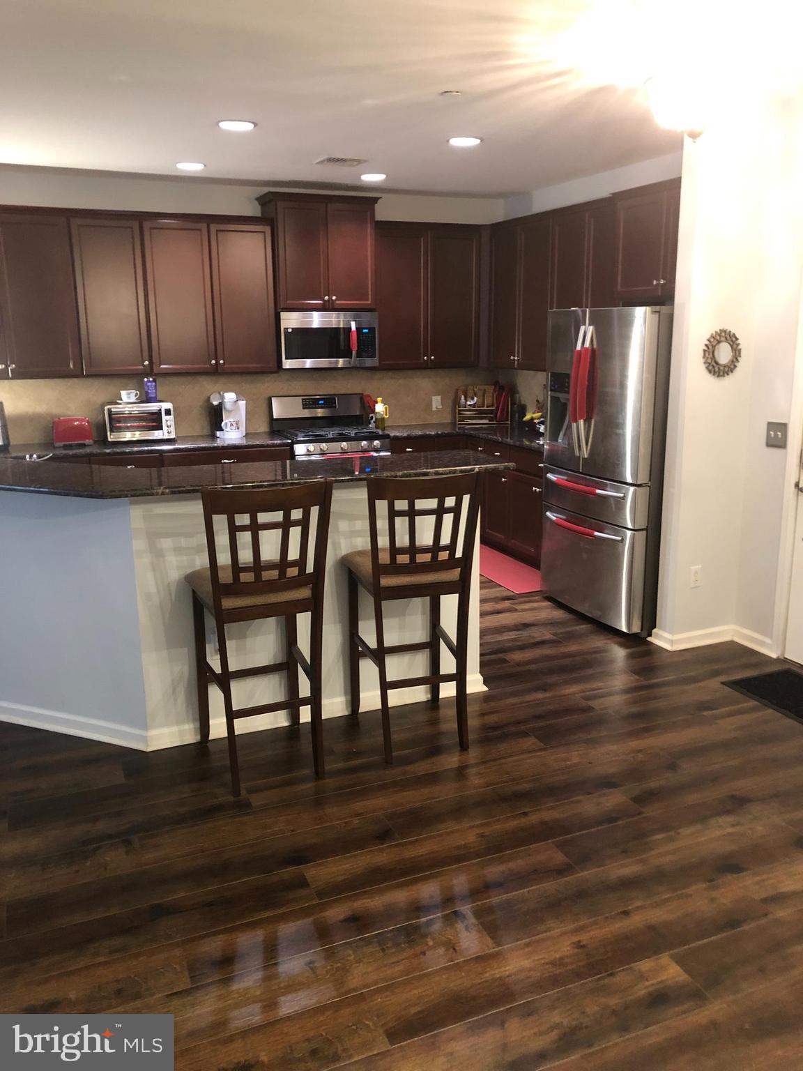 239 Carson Terrace, Unit 239 Huntingdon Valley, PA 19006 - Photo 2 of 19 a kitchen with granite countertop wooden floors wooden cabinets and appliances
