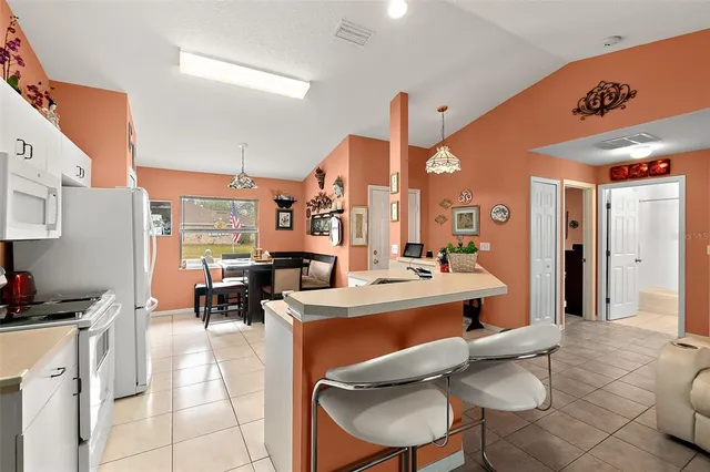 a view of a kitchen with kitchen island stainless steel appliances sink stove and chairs
