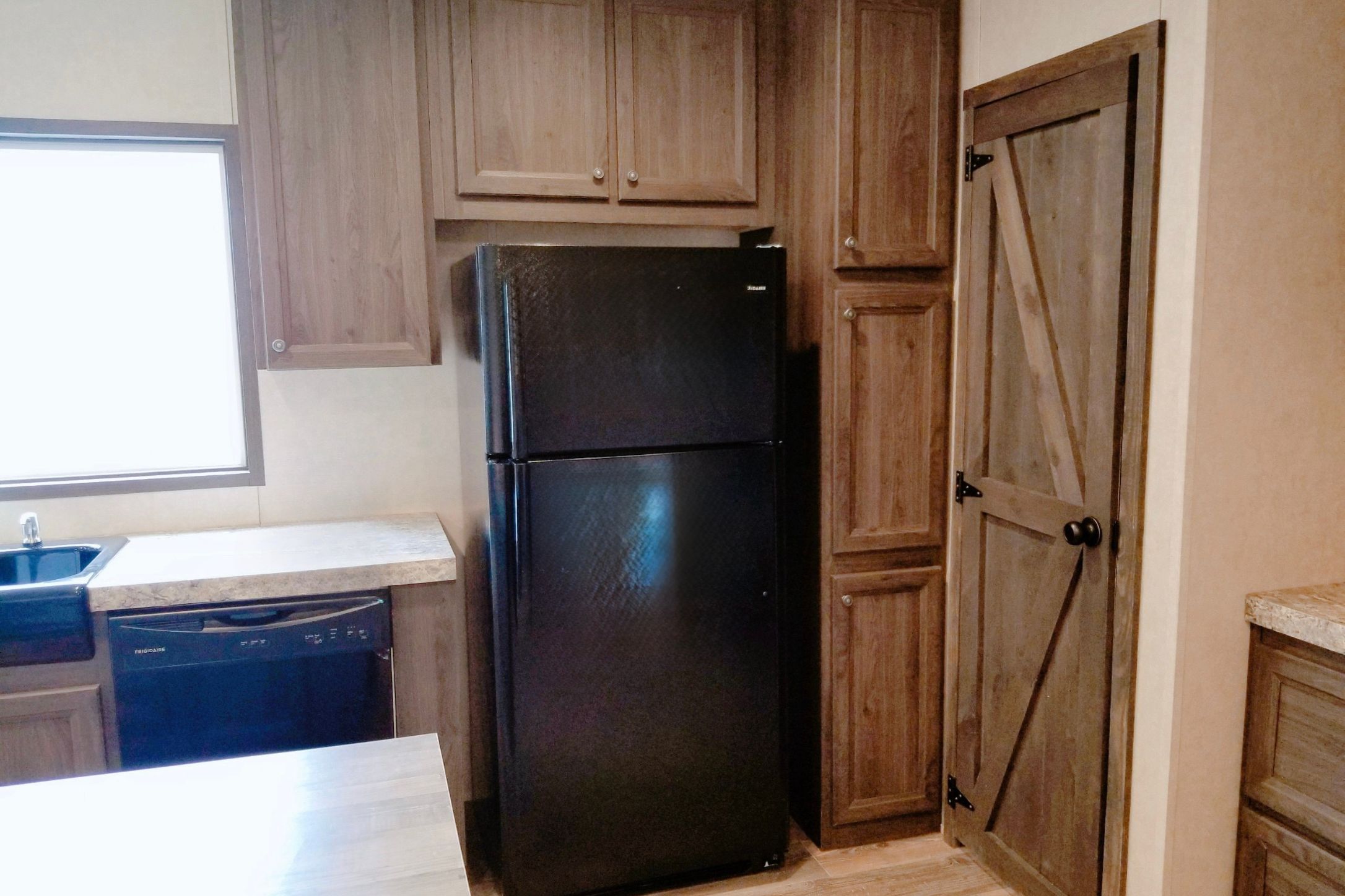 2409 County Road 313 Jarrell, TX 76537 - Photo 8 of 14 Kitchen with light countertops, black appliances, light wood-style floors, and wood finish cabinetry