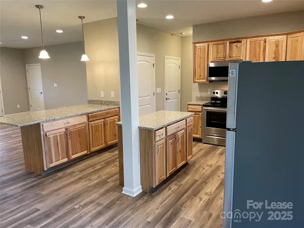 a large kitchen with stainless steel appliances a large counter top a stove a chimney a sink and a refrigerator