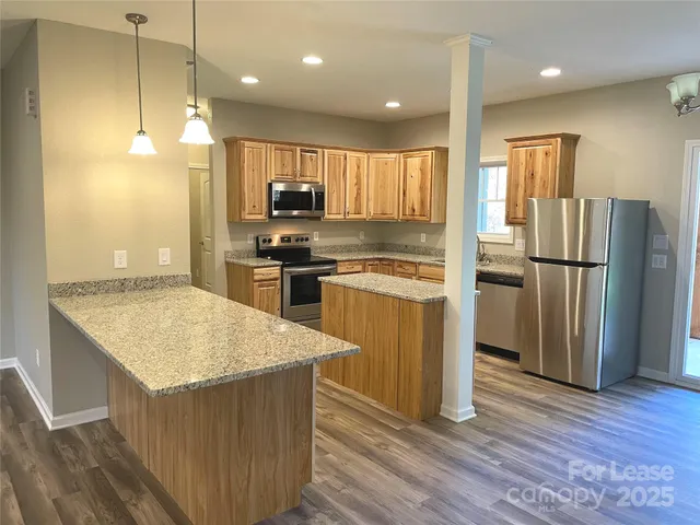 a kitchen with kitchen island a counter top space a refrigerator a sink and a stove