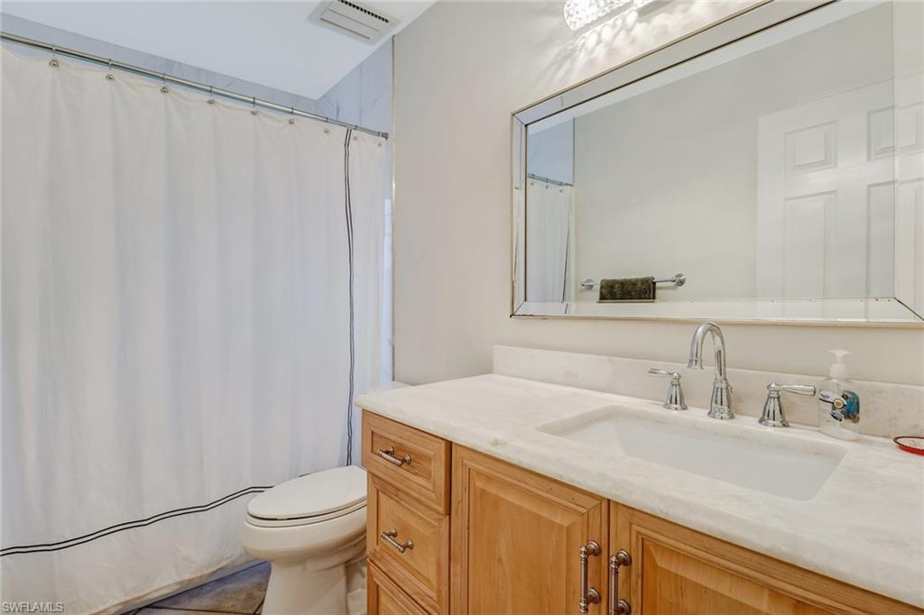 6917 Mill Run Road Naples, FL 34109 - Photo 19 of 29 a bathroom with a sink a toilet a mirror and shower curtain