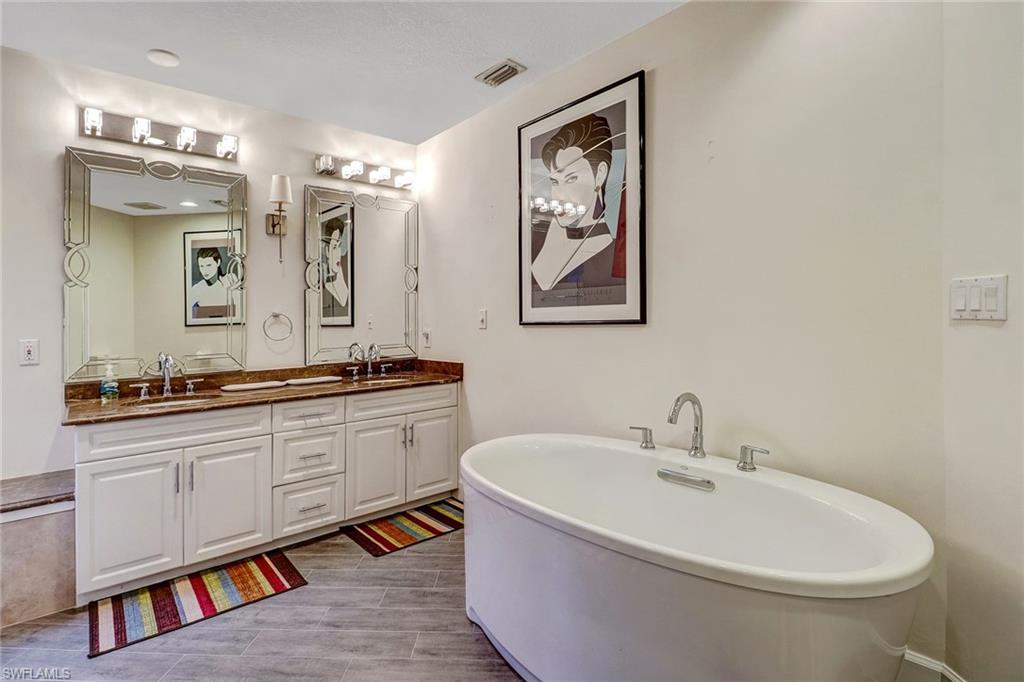6917 Mill Run Road Naples, FL 34109 - Photo 24 of 29 a spacious bathroom with a double vanity sink a mirror and a bathtub