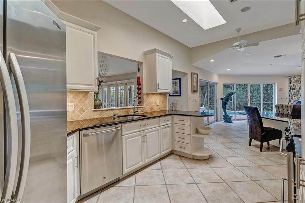 6917 Mill Run Road Naples, FL 34109 - Photo 3 of 29 a large white kitchen with cabinets a sink a window and stainless steel appliances