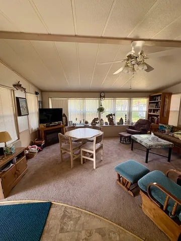 a living room with furniture a flat screen tv and kitchen view