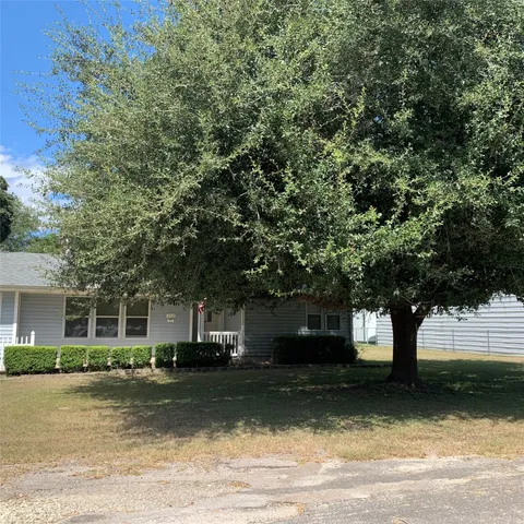 a front view of a house with a garden and trees