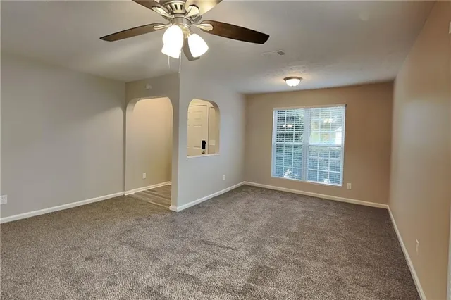 an empty room with a chandelier fan and windows