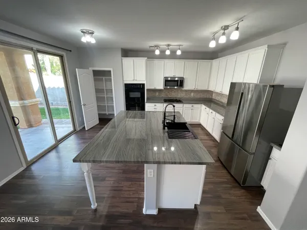 a kitchen with stainless steel appliances granite countertop a refrigerator a stove a sink dishwasher and a stove with wooden floor