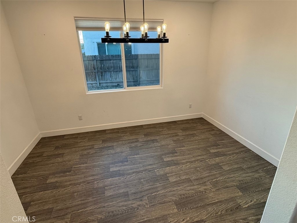 2415 Explorador Drive Merced, CA 95340 - Photo 11 of 28 an empty room with wooden floor chandelier and windows