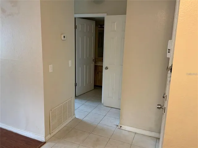 an empty room with wooden floor chandelier fan and windows