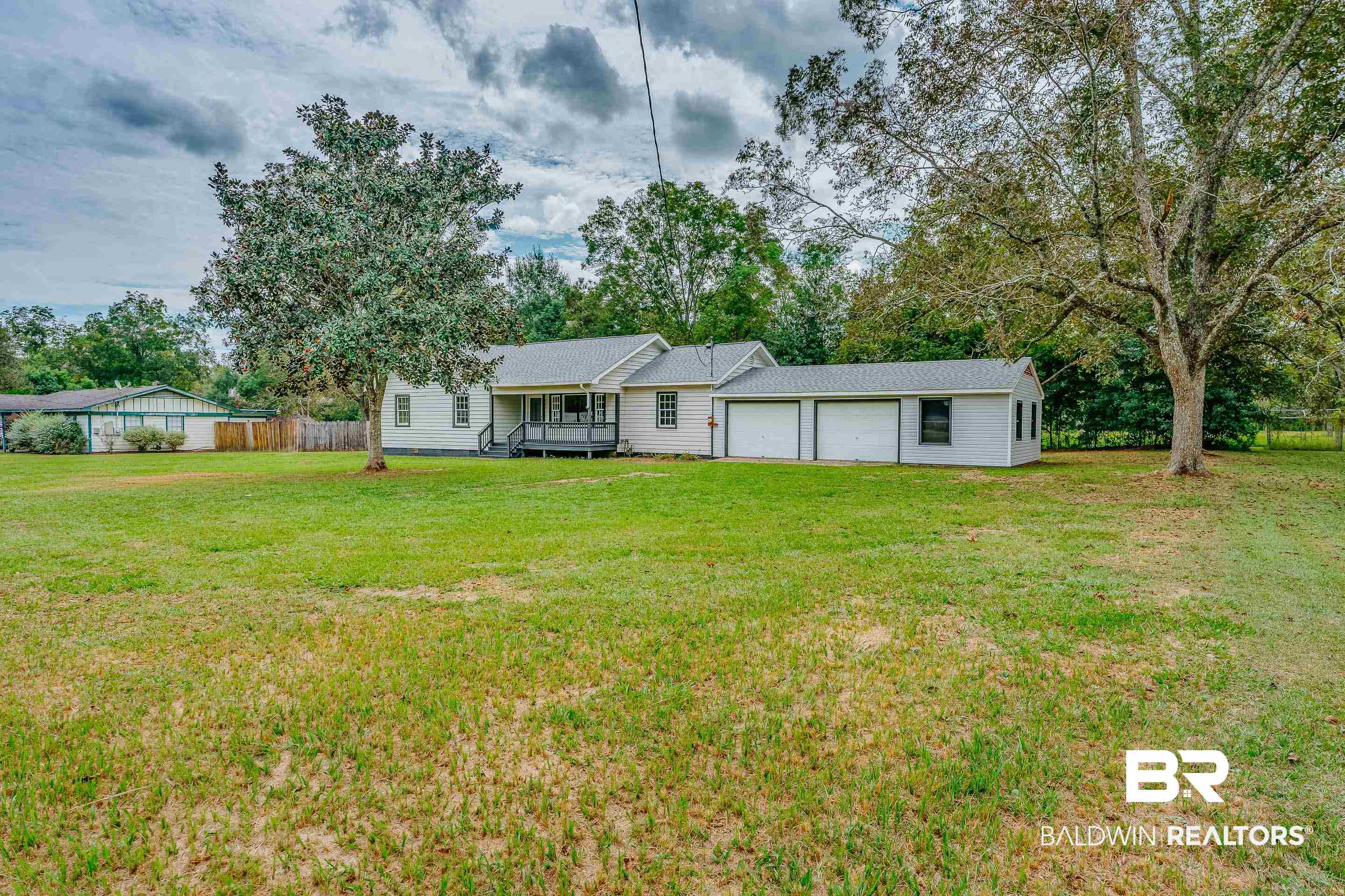 8001 16th Street Irvington, AL 36544 - Photo 33 of 35 View of front of house with a garage, view of scattered trees, and a deck