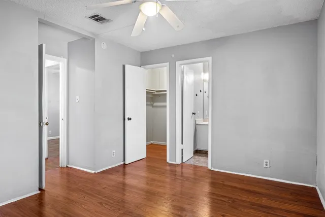 an empty room with wooden floor and a ceiling fan