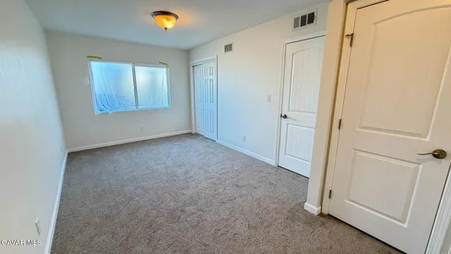 a view of an empty room and bedroom with wooden floor