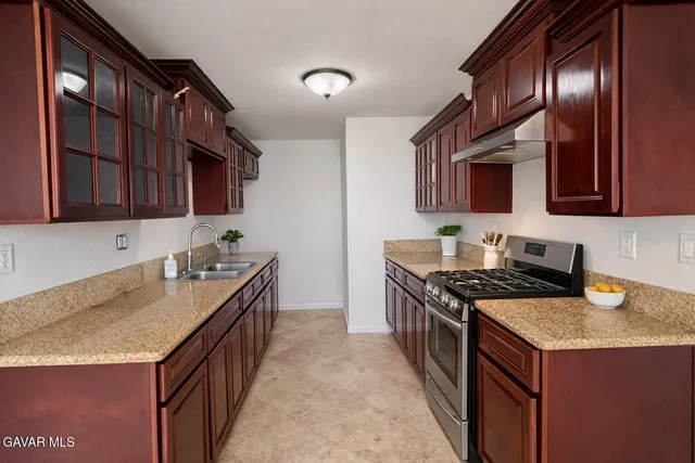 a kitchen with granite countertop a sink a stove and cabinets