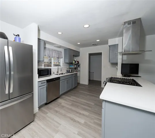 a kitchen with stainless steel appliances a refrigerator a stove a sink and a refrigerator