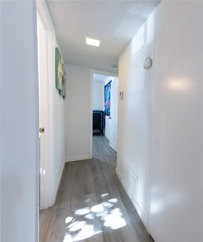 a view of a hallway with wooden floor and a bathroom
