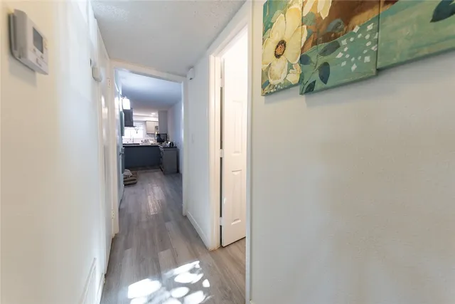 a view of a hallway with wooden floor windows and a bathroom