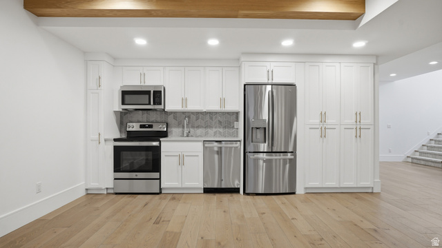 1682 North 1950 W Street, Unit 9 Provo, UT 84604 - Photo 47 of 84 Kitchenette featuring stainless steel appliances, white cabinetry with gold-tone hardware, a gray herringbone tile backsplash, and light wood-finish flooring
