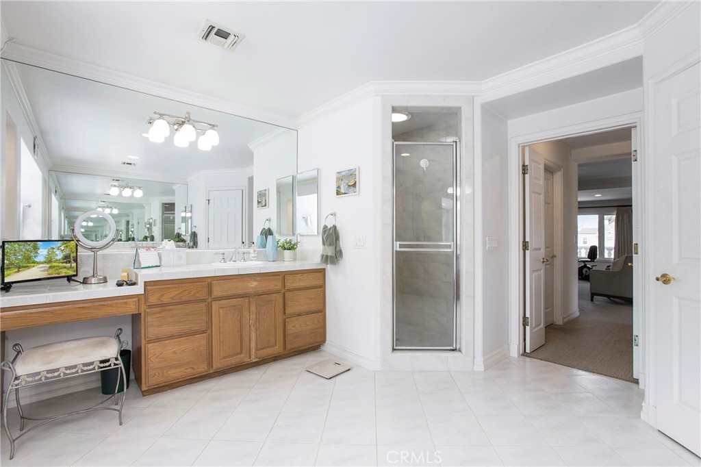 11376 Loch Lomond Road Los Alamitos, CA 90720 - Photo 21 of 32 a large bathroom with a glass door shower sink and a mirror