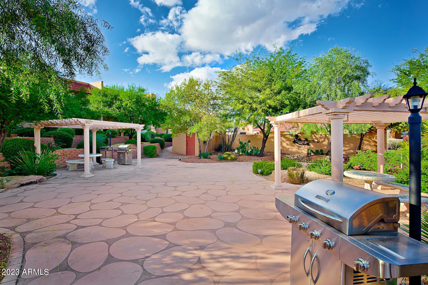 540 South West Road, Unit 24 Wickenburg, AZ 85390 - Photo 22 of 23 a view of a patio with table and chairs under an umbrella with large trees