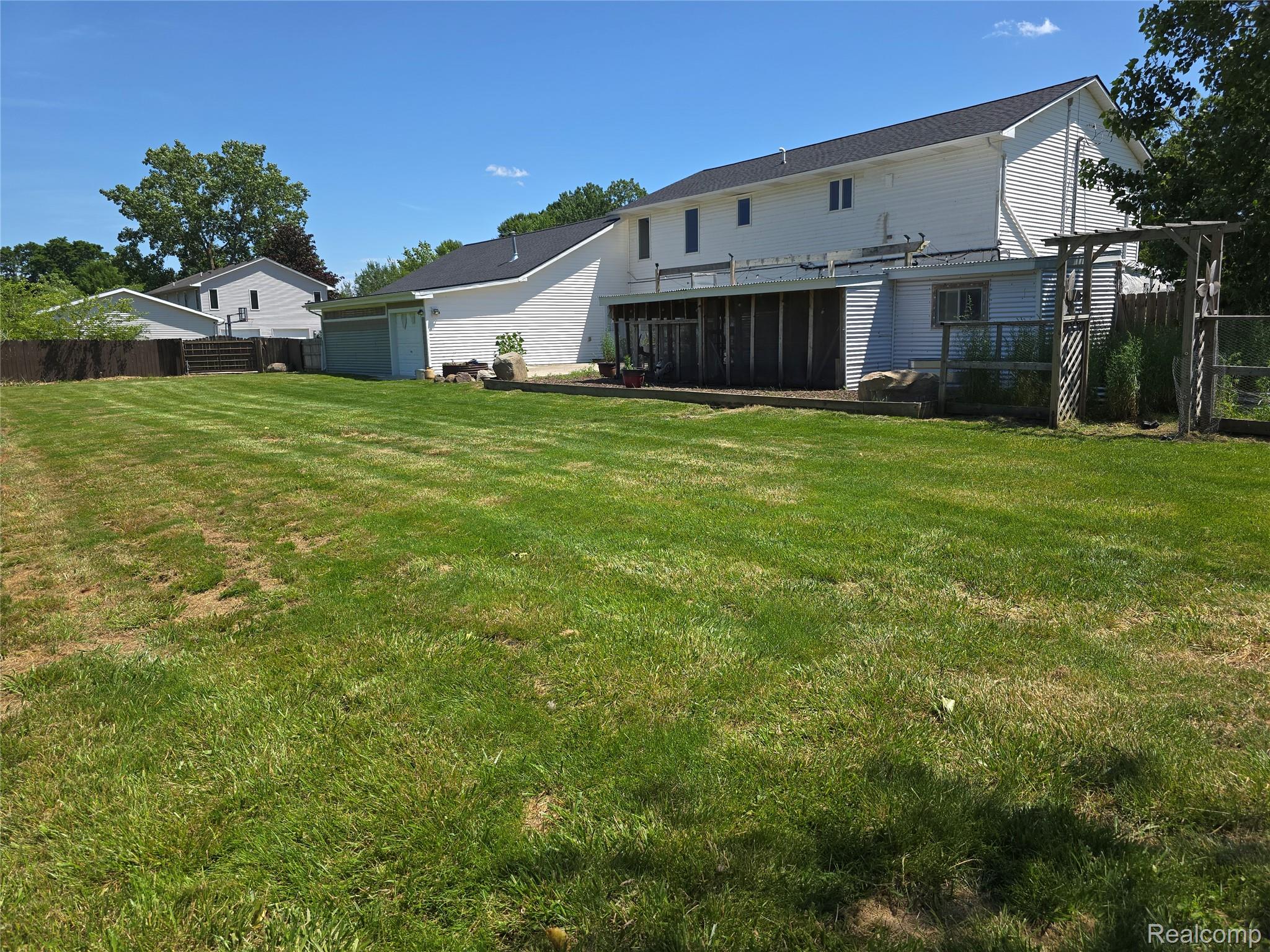 5158 Coldwater Road Columbiaville, MI 48421 - Photo 22 of 25 Expansive lawn area with a white two-story exterior, a dark shingle roof, and a wood lattice structure