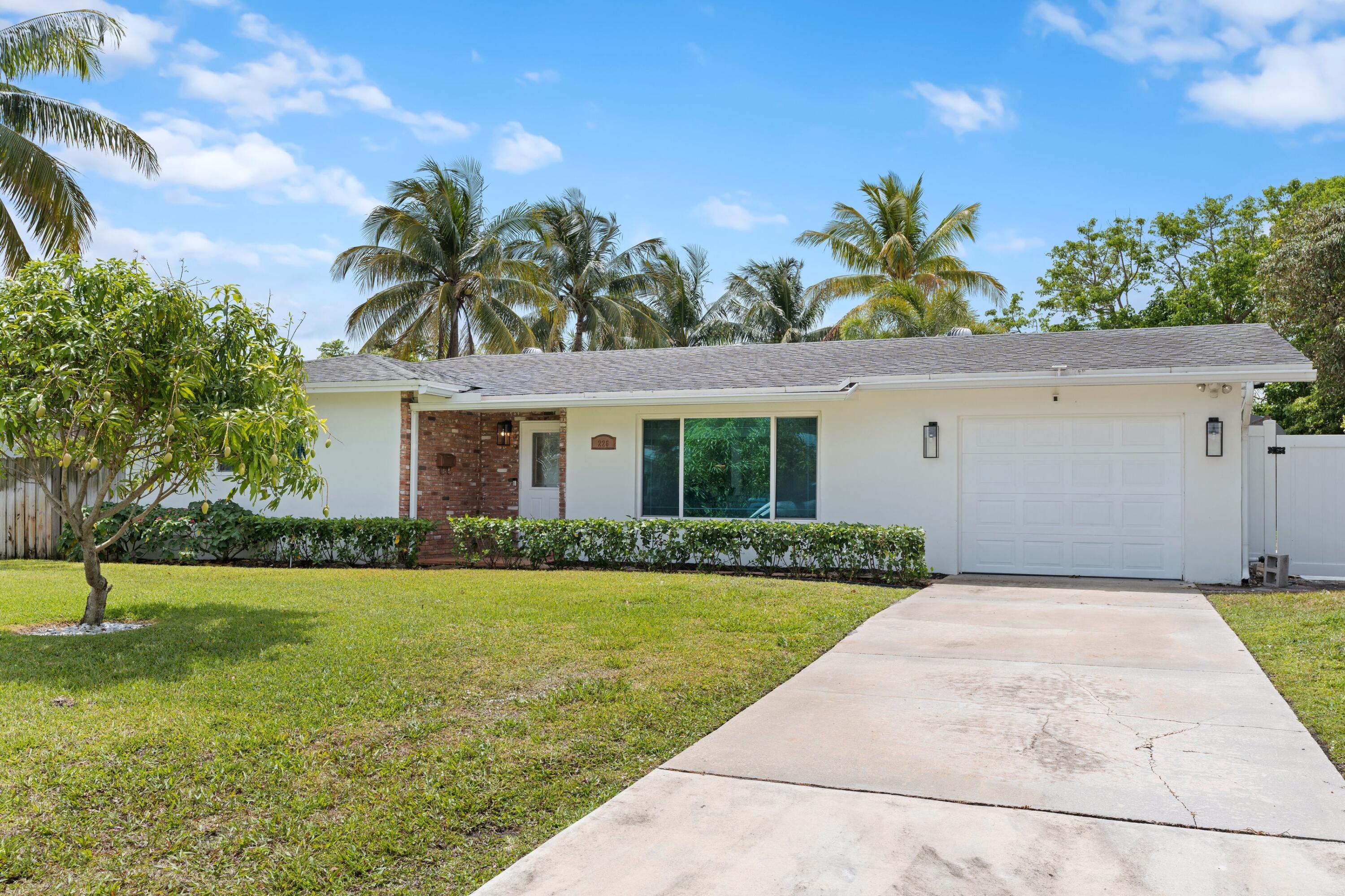 226 Southwest 13th Avenue Boynton Beach, FL 33435 - Photo 2 of 16 a front view of a house with a yard and garage