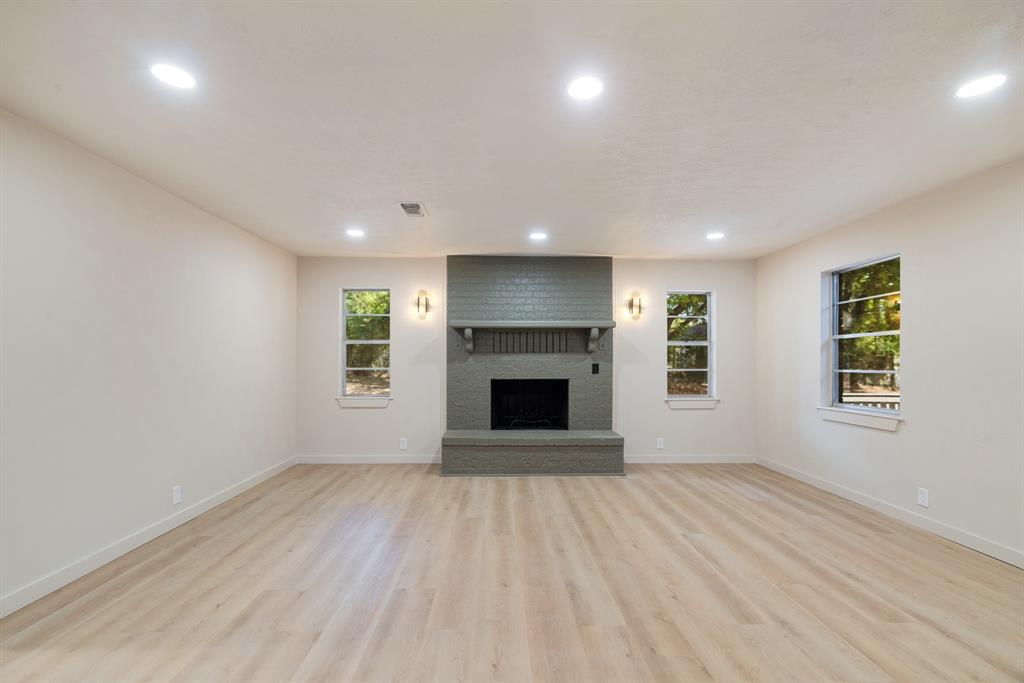 an empty room with windows and fireplace
