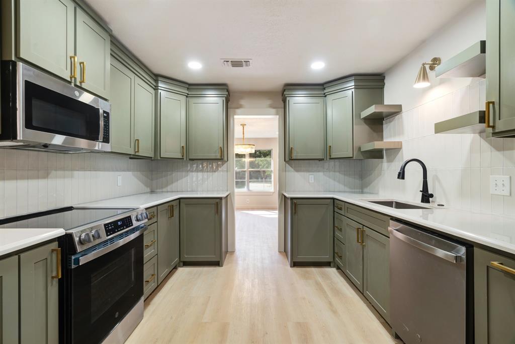 1195 33rd Street Southeast Paris, TX 75460 - Photo 8 of 34 a kitchen with stainless steel appliances granite countertop a sink and a stove top oven with wooden floor