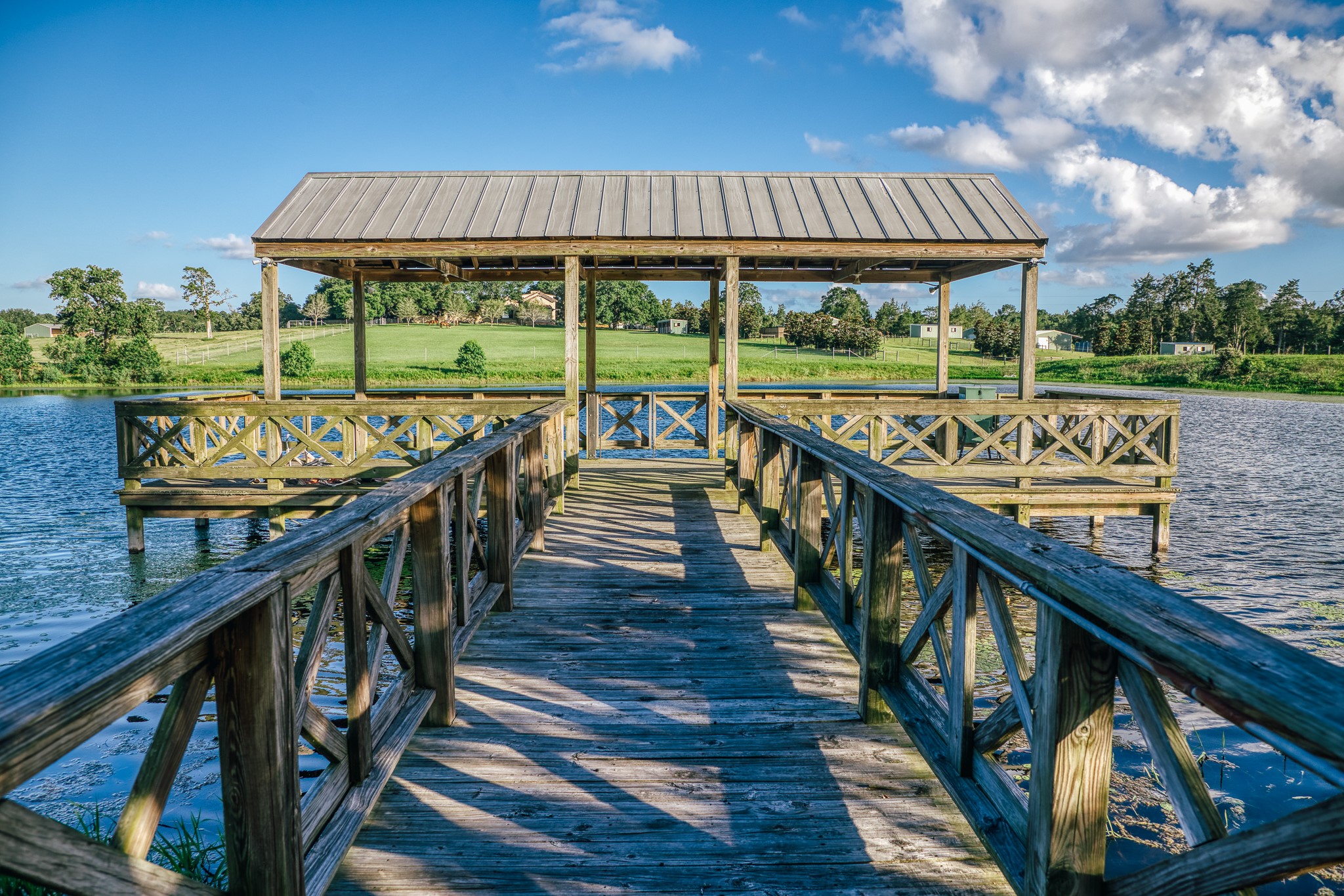 1034 Hilbun Road New Ulm, TX 78950 - Photo 40 of 49 The picturesque covered dock overlooks the property's stunning 7-acre stocked lake, offering a private retreat for fishing, sunset gatherings, and waterfront relaxation.