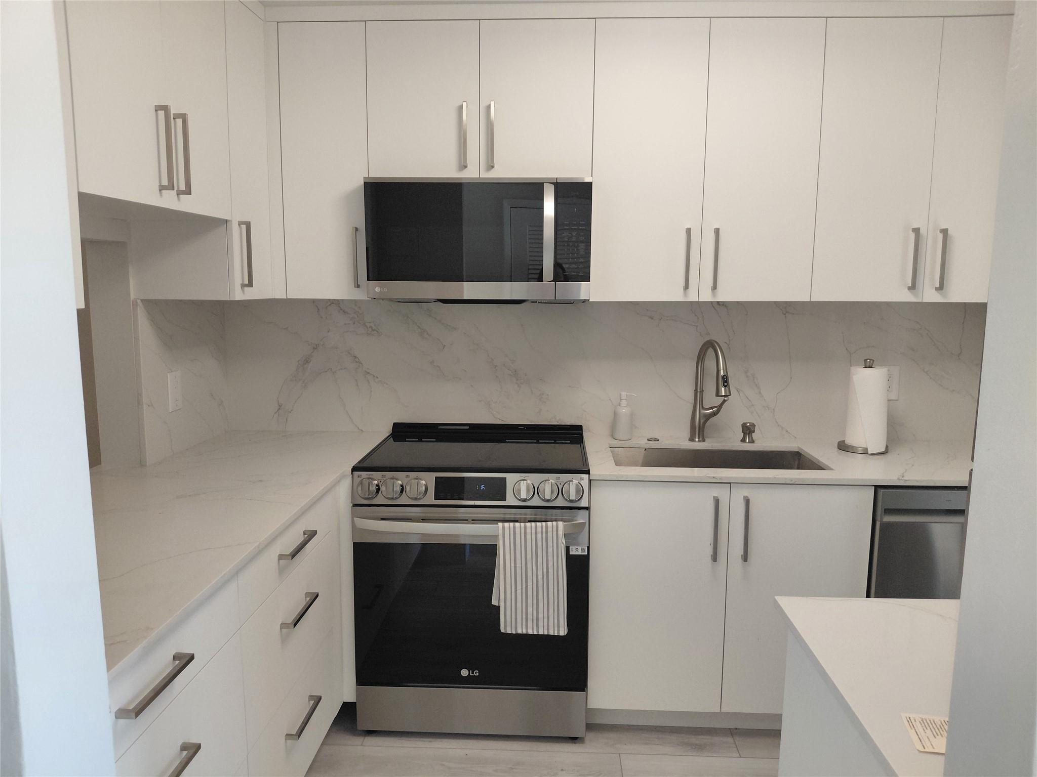 1951 Northeast 39th Street, Unit 127 Lighthouse Point, FL 33064 - Photo 2 of 35 a kitchen with stainless steel appliances a stove a microwave and cabinets