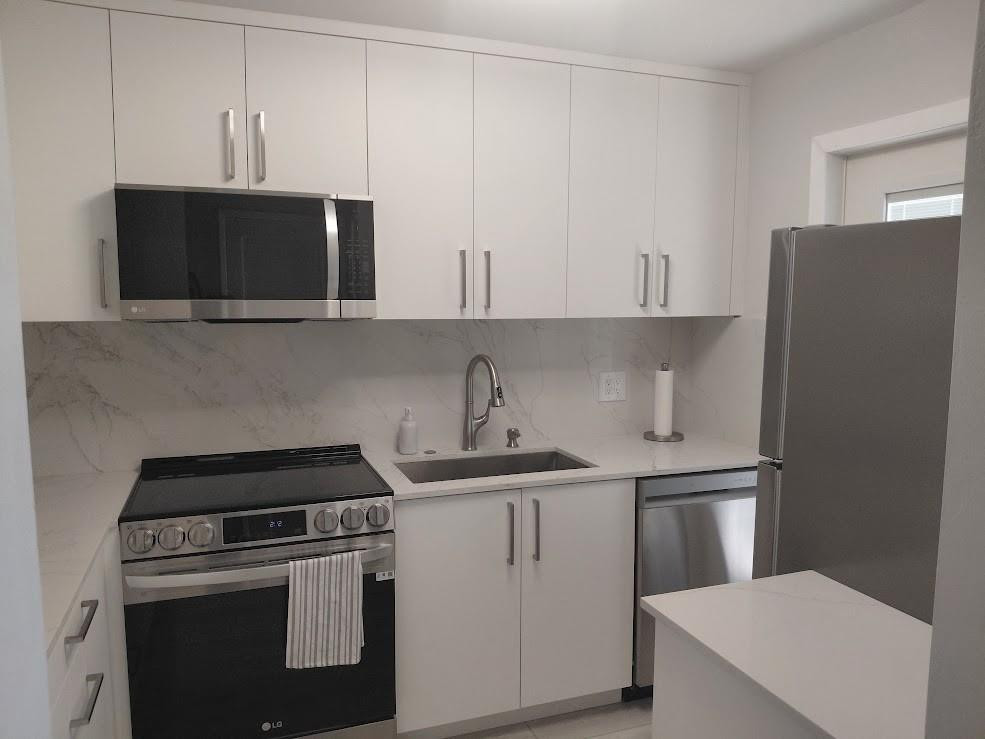 1951 Northeast 39th Street, Unit 127 Lighthouse Point, FL 33064 - Photo 4 of 35 a kitchen with a sink and a stove