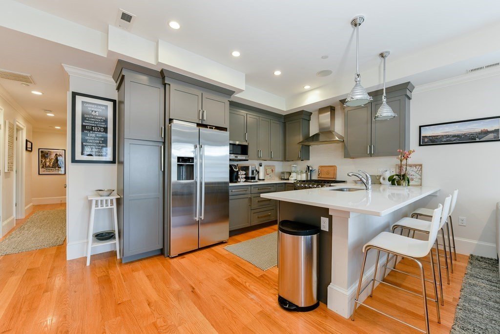 a kitchen with stainless steel appliances granite countertop a refrigerator a sink a stove and a refrigerator
