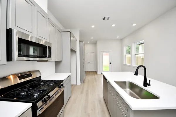 a large kitchen with stainless steel appliances granite countertop a lot of cabinets a stove and a refrigerator