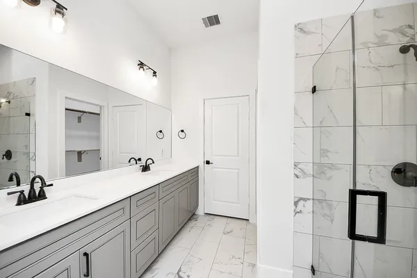 a bathroom with a double vanity sink a mirror and shower