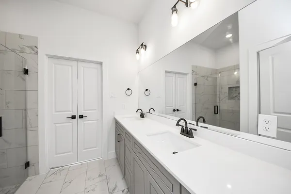 a bathroom with a double vanity sink mirror and shower