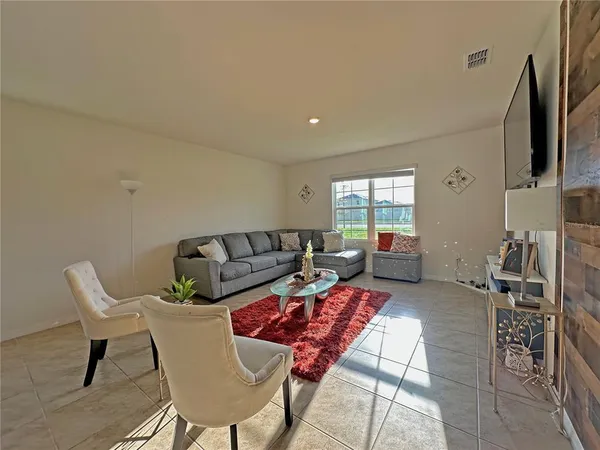 a living room with furniture a flat screen tv and a window