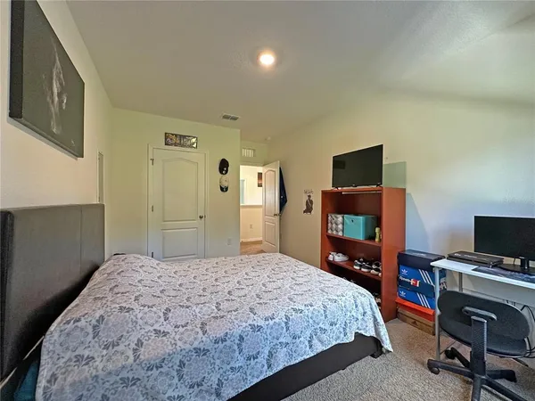 a bedroom with a bed and a flat tv screen on a dresser
