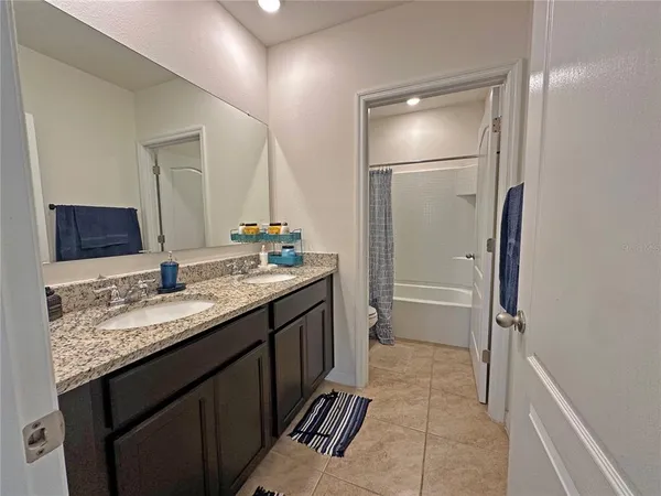 a bathroom with a granite countertop sink a mirror and a shower