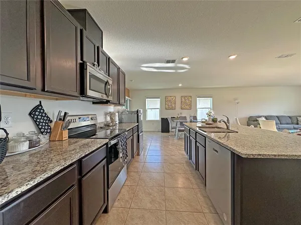 a kitchen with stainless steel appliances granite countertop a sink a stove and a wooden floors