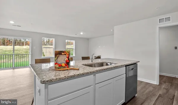 a kitchen with white cabinets stainless steel appliances and wooden floor