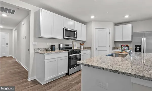 a kitchen with granite countertop a sink stove refrigerator and cabinets