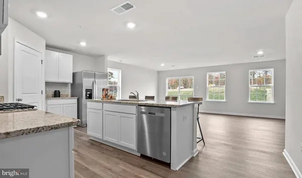 a kitchen with stainless steel appliances granite countertop a dining table chairs refrigerator and sink