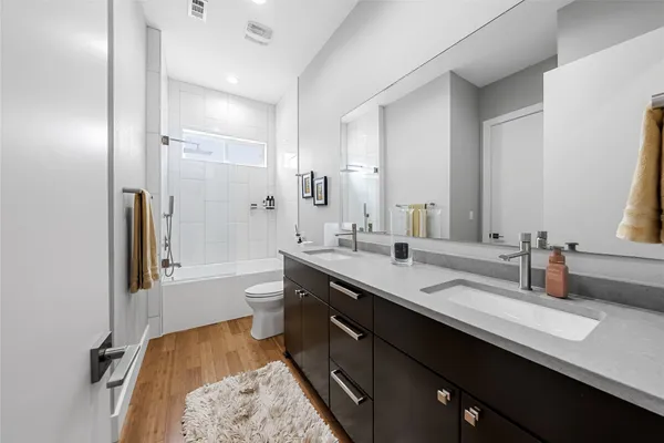 a spacious bathroom with a granite countertop sink toilet mirror and bathtub