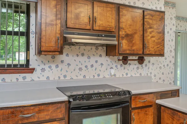 a large kitchen with stainless steel appliances kitchen island granite countertop a refrigerator and a sink