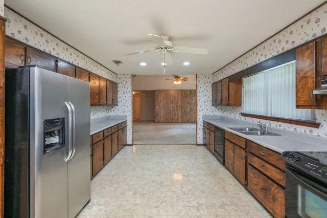 a living room with stainless steel appliances furniture a rug and a kitchen view