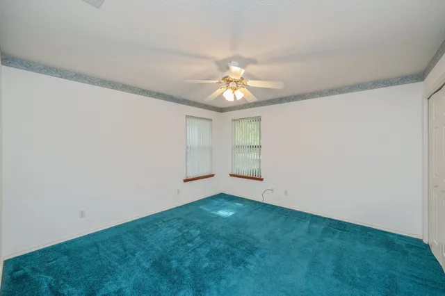 an empty room with a ceiling fan and a window