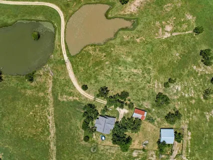 an aerial view of a residential houses with outdoor space and trees