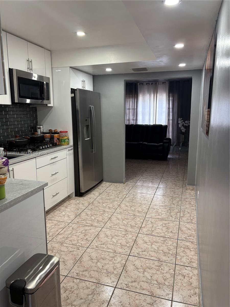 821 East 13th Street Hialeah, FL 33010 - Photo 12 of 25 a kitchen with granite countertop a refrigerator and a stove top oven